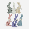 Set of pastel-colored rabbit figurines with white bows on a white background