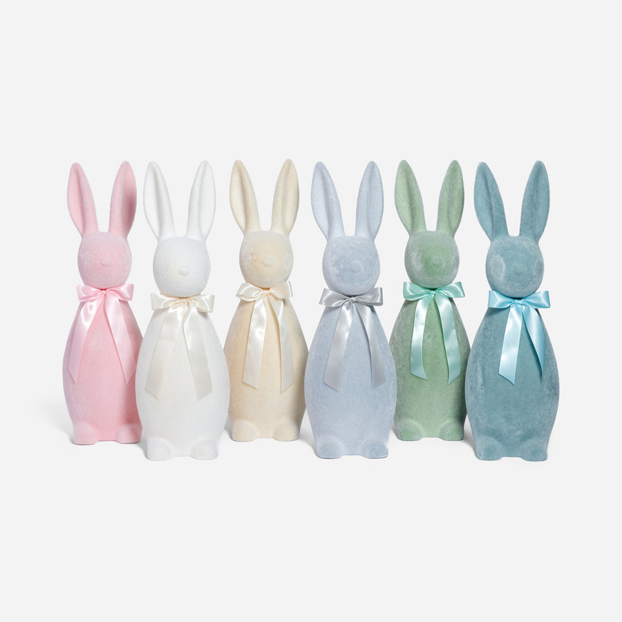 Set of six pastel-colored rabbit-shaped bottles with ribbons on a white background