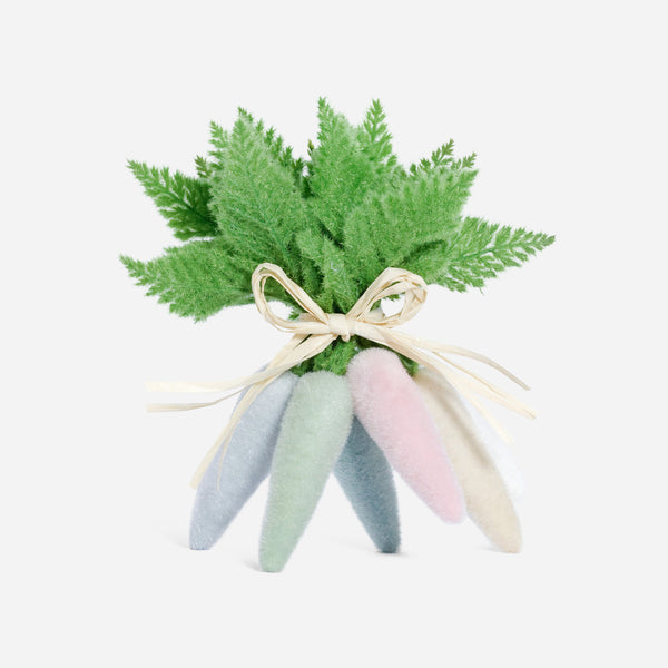 Pastel-colored bunny toys with a small green plant on a white background