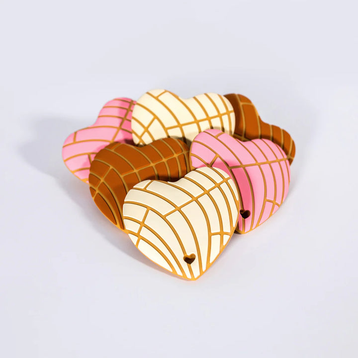 Heart-shaped cookie with pink, white, and brown patterns on a light gray background