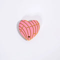 Heart-shaped pink and gold decorative item on a white background