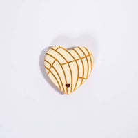 Heart-shaped wooden ornament with wicker pattern on a light purple background