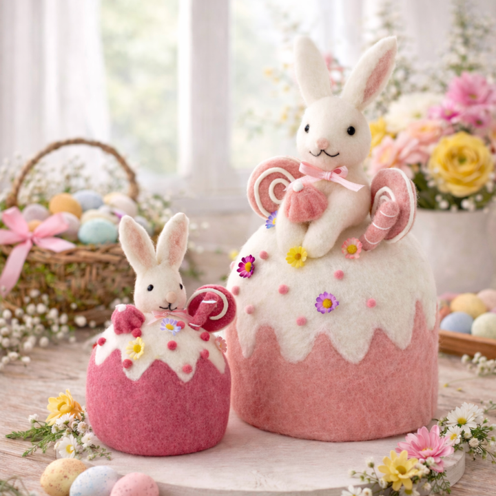 Two decorative Easter bunnies in pink and white egg-shaped containers with candy on a wooden table.