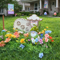 Decorative Easter scene with sheep, gnome, and flowers in a front yard.