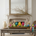 Decorative Easter display on a wooden table with colorful eggs and rabbits, against a neutral wall.