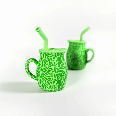 Two green silicone pitchers with leaf patterns and straws on a white background