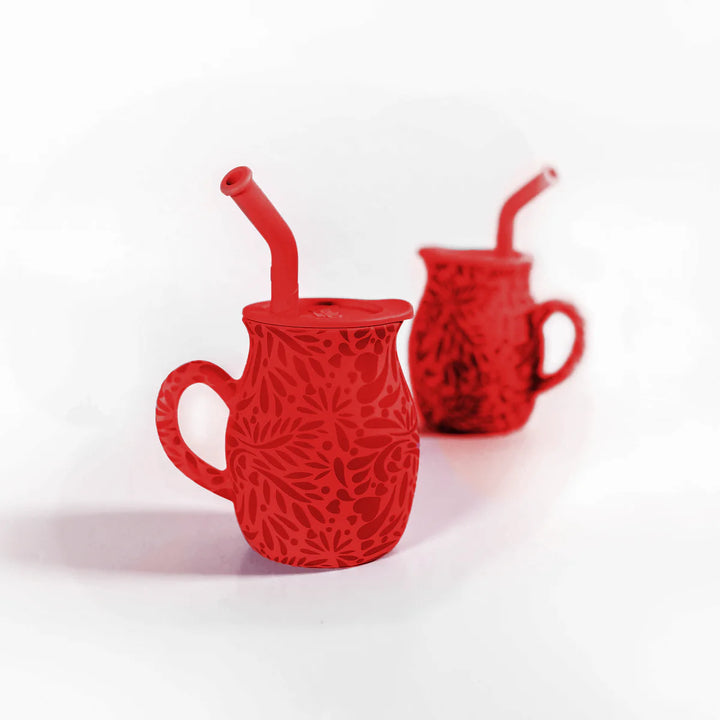 Two red textured mugs with straws on a white background
