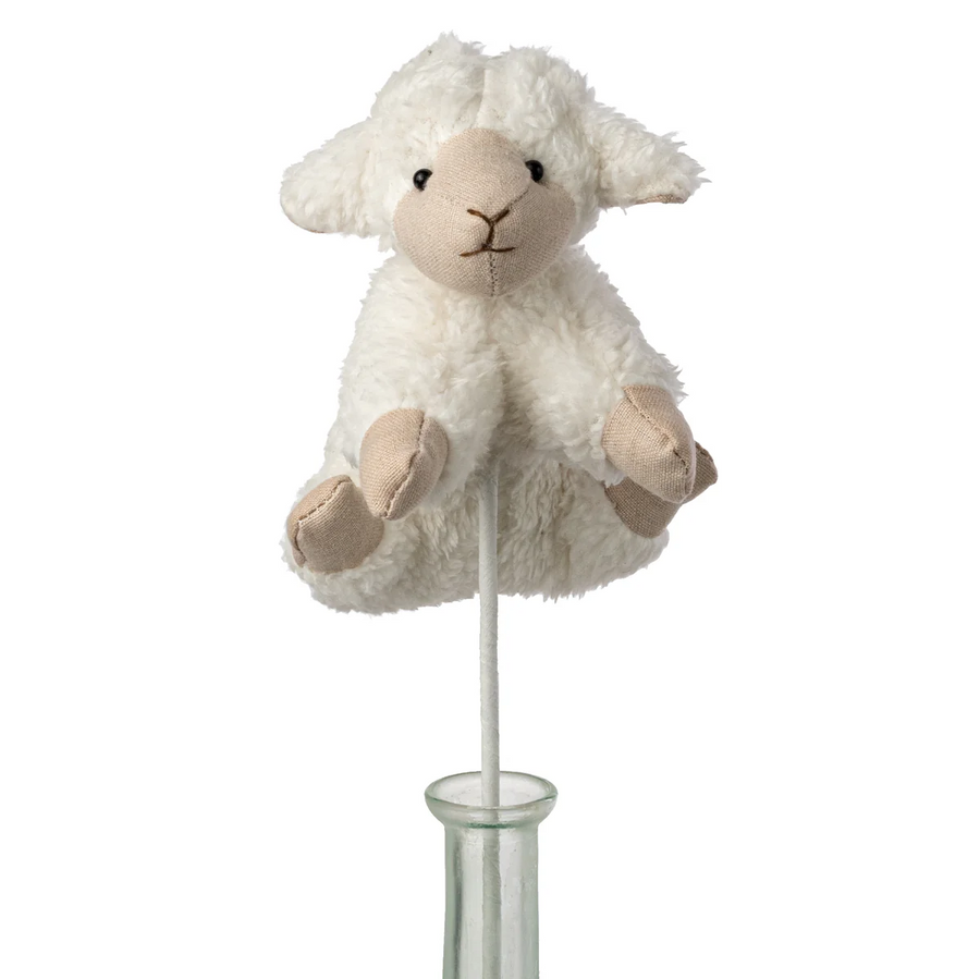 White plush lamb toy on a stand against a white background