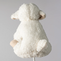 White fluffy lamb toy on a stand against a gray background