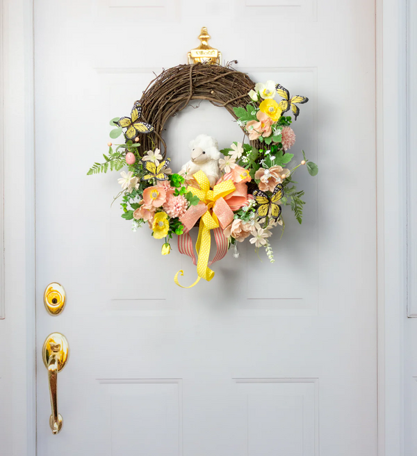 Decorative wreath with flowers and a small dog figurine on a door.
